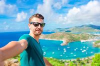 Young man taking selfie with view of English Harbor from Shirley Heights, Antigua